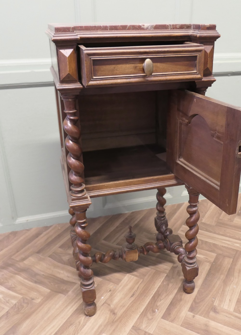 An antique French walnut night table featuring a marble top, a carved drawer, a lower cupboard door with foliate carvings, and barley twist legs. View VII