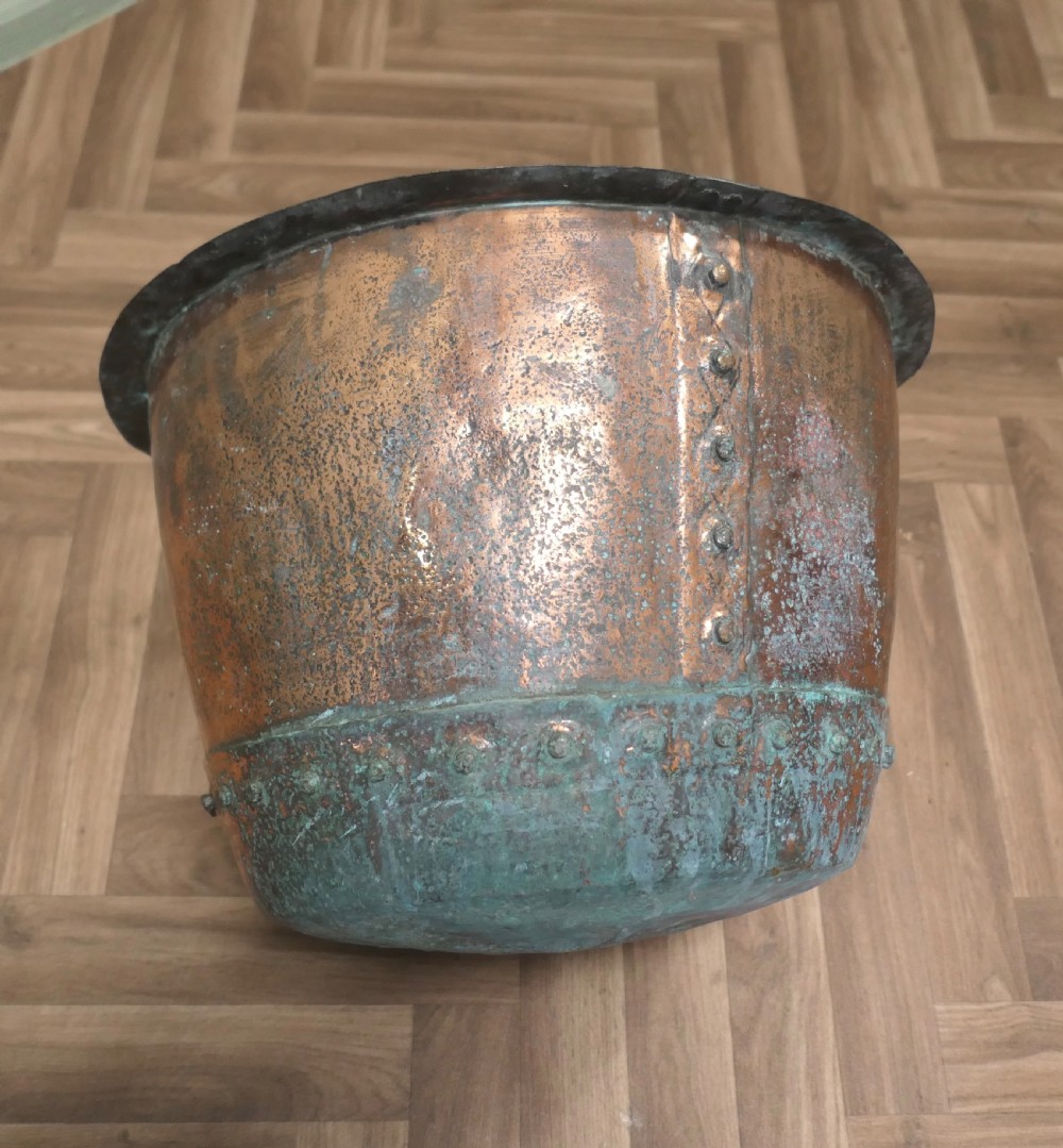 A 19th-century deep copper vessel featuring hand-riveted vertical and base seams with a wide flared rim and natural surface patina. View V