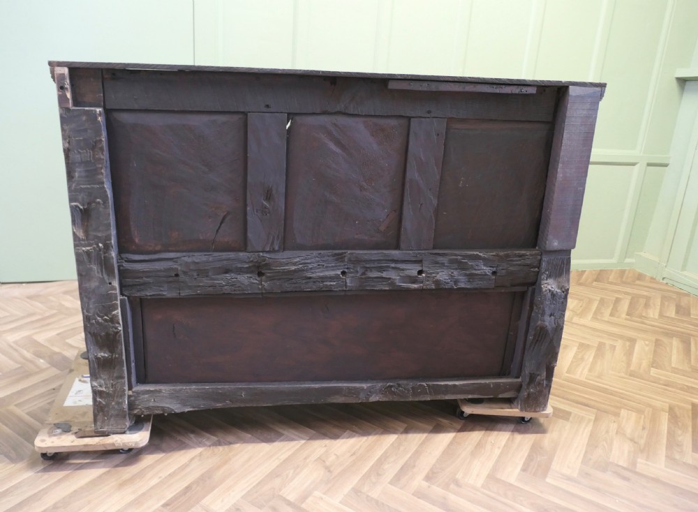 A dark carved oak high back box settle featuring three carved back panels, a hinged seat, and carved front base panels. View V