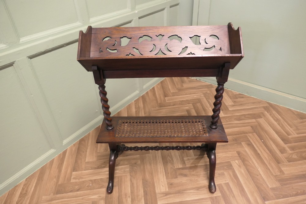 An oak book stand featuring a sloped upper shelf, barley twist supports, an woven cane lower shelf, and cabriole legs. View V