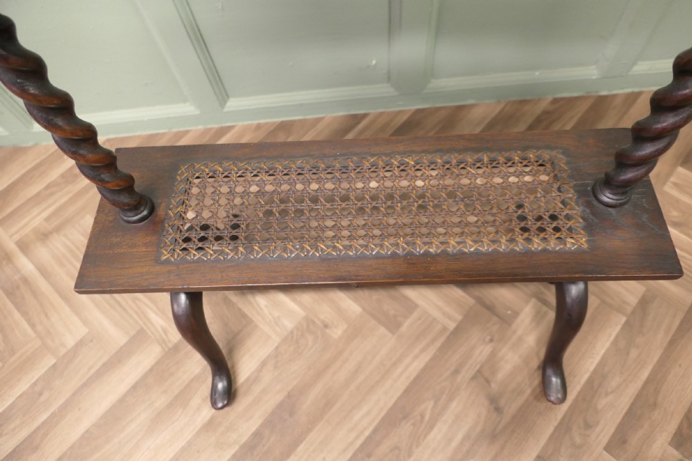 An oak book stand featuring a sloped upper shelf, barley twist supports, an woven cane lower shelf, and cabriole legs. View VII