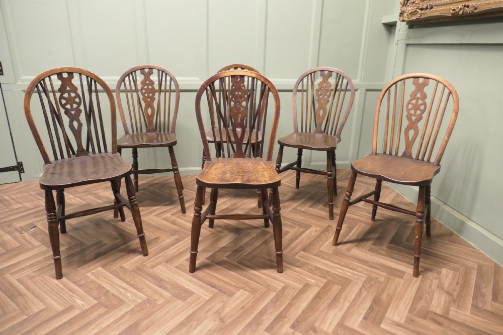 A harlequin set of six antique beech and elm wheelback Windsor dining chairs with turned legs and hoop backs.