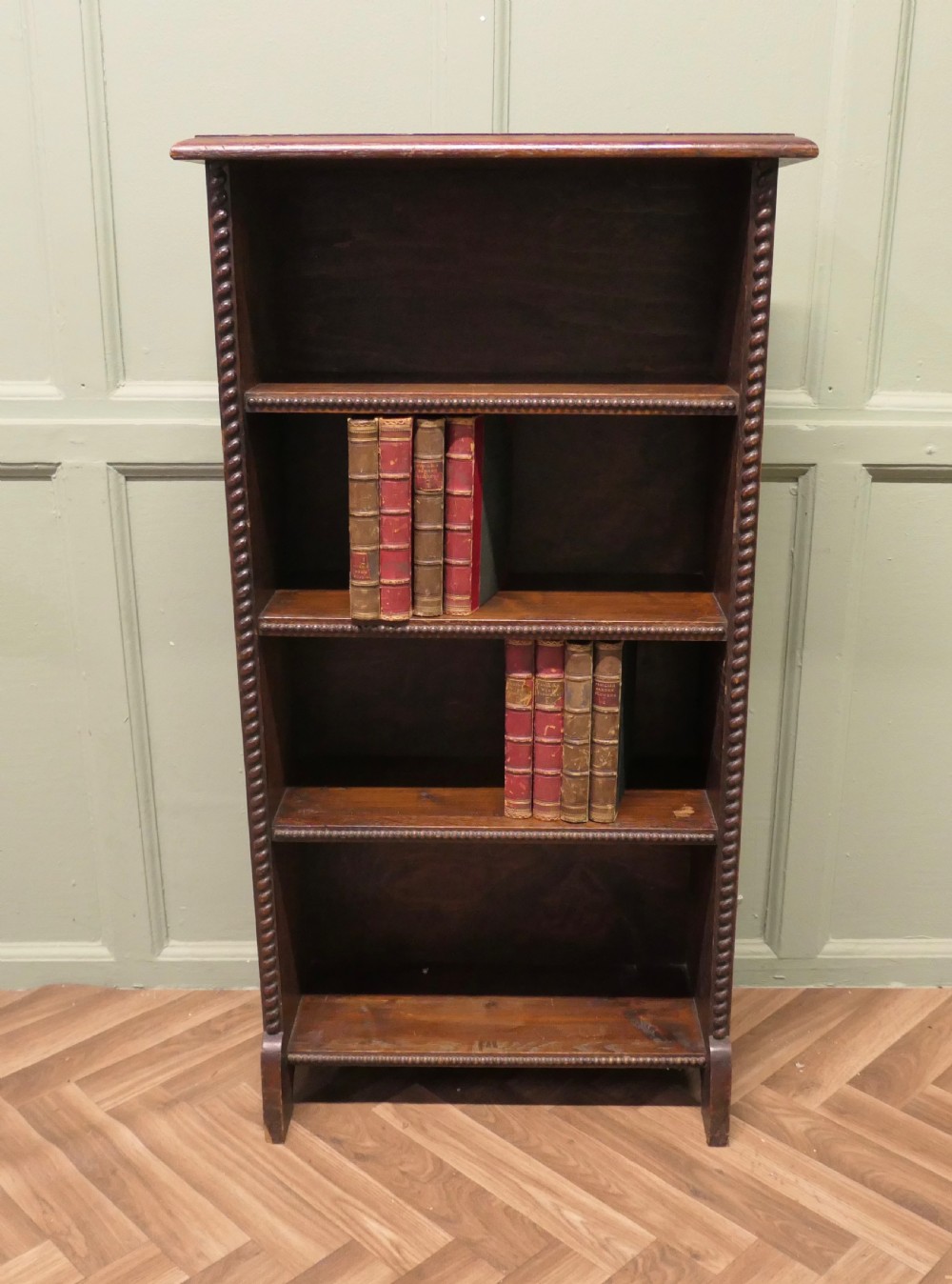 An early 20th-century open dark oak bookcase featuring four shelves flanked by carved beaded moulding along the outer vertical edges. View II