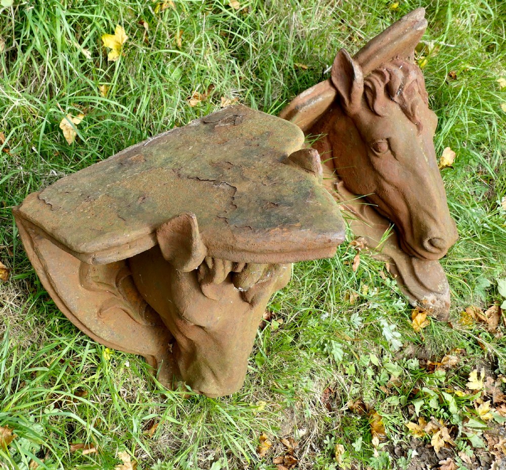 A pair of heavy cast iron wall brackets shaped as detailed horse heads with textured manes and integrated shelf support plates, displaying surface rust patina. View IV