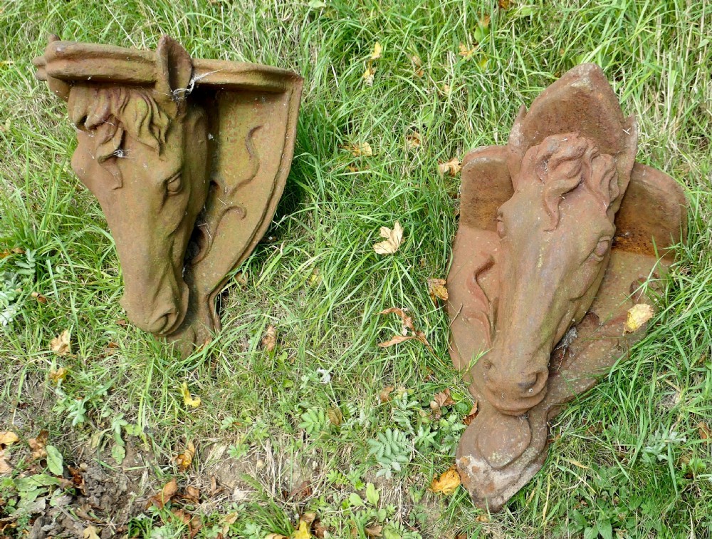 A pair of heavy cast iron wall brackets shaped as detailed horse heads with textured manes and integrated shelf support plates, displaying surface rust patina. View VI