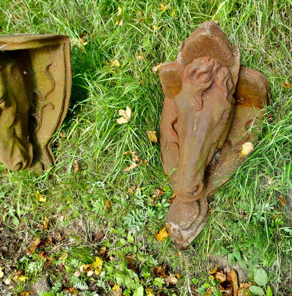 A pair of heavy cast iron wall brackets shaped as detailed horse heads with textured manes and integrated shelf support plates, displaying surface rust patina. View VII