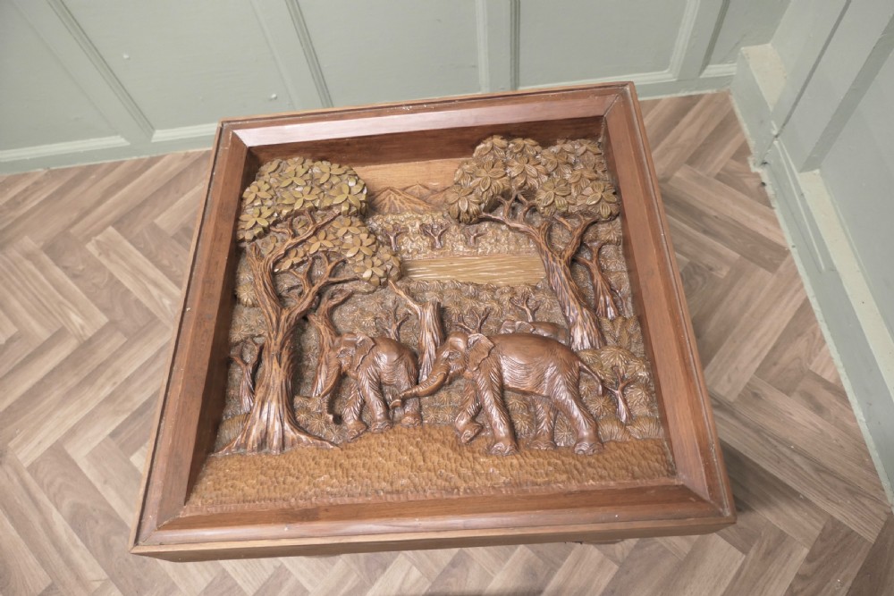 A three-piece teak table set featuring elaborate relief carvings of elephants amidst trees under glass tops. View VII