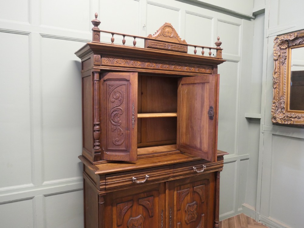 A two-tier carved oak French buffet de corps featuring a central high-relief panel depicting a hunting scene, spindled top gallery, and two-door lower base. View V