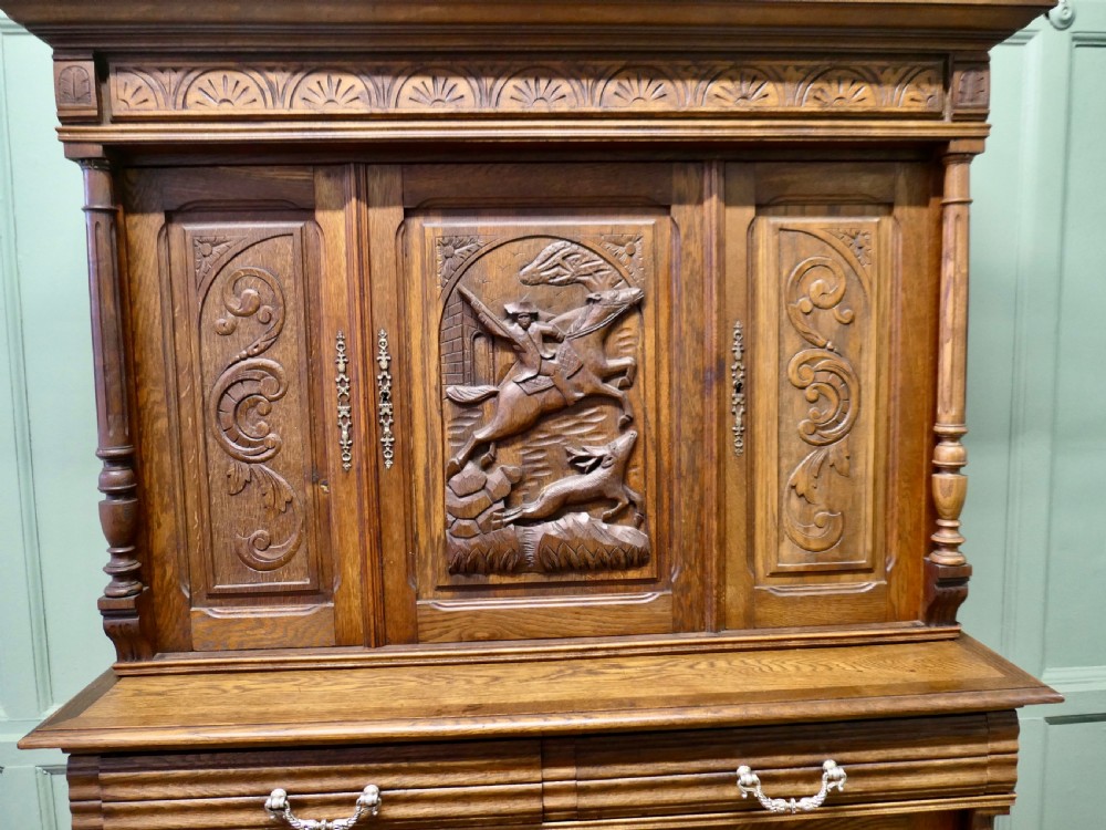 A two-tier carved oak French buffet de corps featuring a central high-relief panel depicting a hunting scene, spindled top gallery, and two-door lower base. View VI