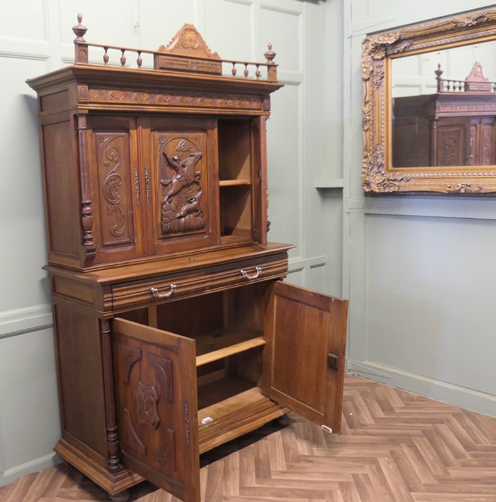 A two-tier carved oak French buffet de corps featuring a central high-relief panel depicting a hunting scene, spindled top gallery, and two-door lower base. View VII