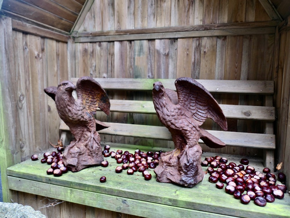 A pair of weathered cast iron eagle statues with outstretched wings perched on textured rock bases featuring a heavy rust patina. View II