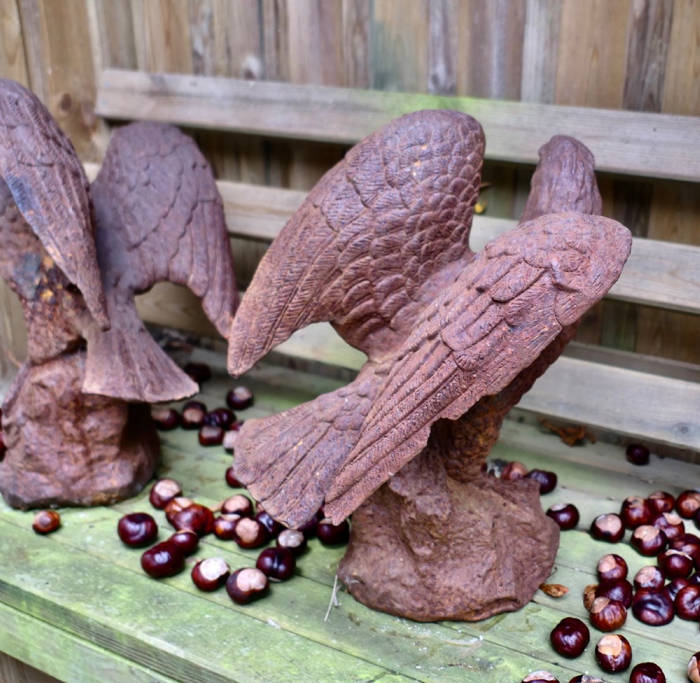A pair of weathered cast iron eagle statues with outstretched wings perched on textured rock bases featuring a heavy rust patina. View VI