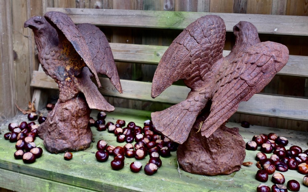 A pair of weathered cast iron eagle statues with outstretched wings perched on textured rock bases featuring a heavy rust patina. View VII