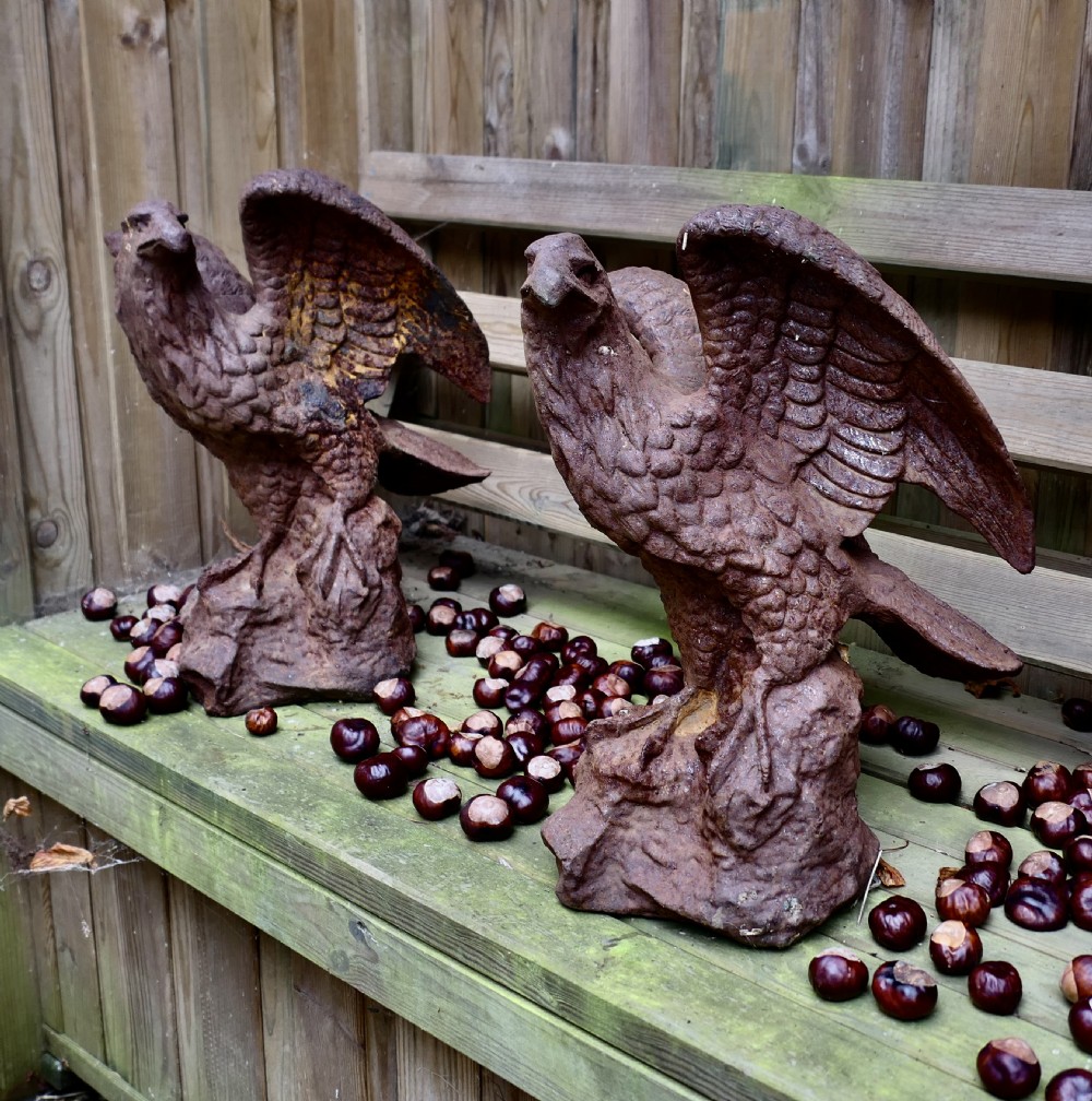 A pair of weathered cast iron eagle statues with outstretched wings perched on textured rock bases featuring a heavy rust patina. View VIII