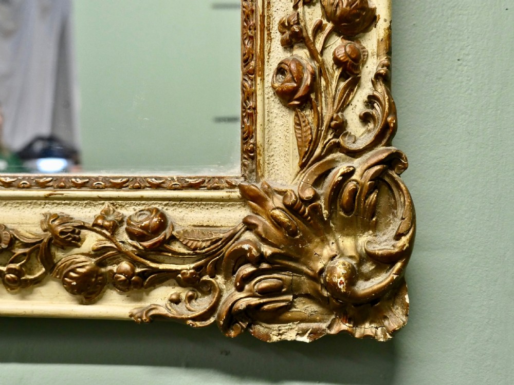 A rectangular French Rococo style wall mirror featuring a painted cream frame adorned with carved gilt floral and scroll ornamentation. View V
