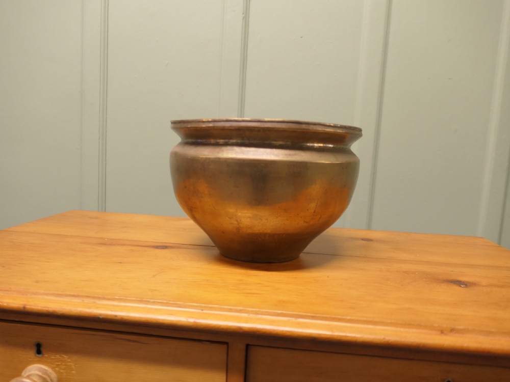 A nineteenth-century brass planter featuring a rounded bulbous body, narrow base, and flared rim with natural surface patination.