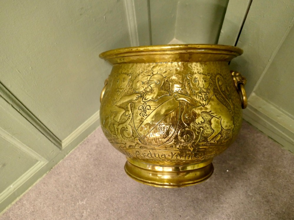 A nineteenth-century embossed brass jardiniere featuring heraldic lion motifs, a shield crest, lion head side handles, and a stepped pedestal base. View VI