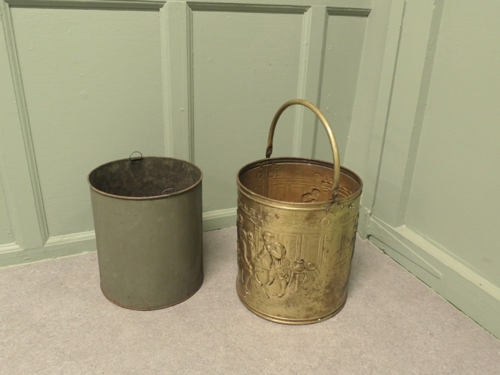 A cylindrical brass coal bucket featuring embossed tavern scenes in relief and a curved swing handle. View VI