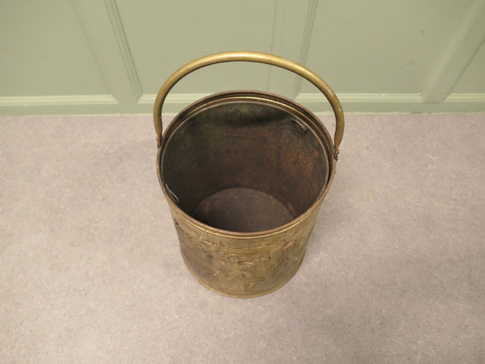 A cylindrical brass coal bucket featuring embossed tavern scenes in relief and a curved swing handle. View VII