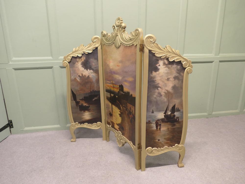 A three-panel folding fire screen with a carved gold giltwood frame and oil-painted maritime scenes depicting ships near a coastal shore at sunset. View III