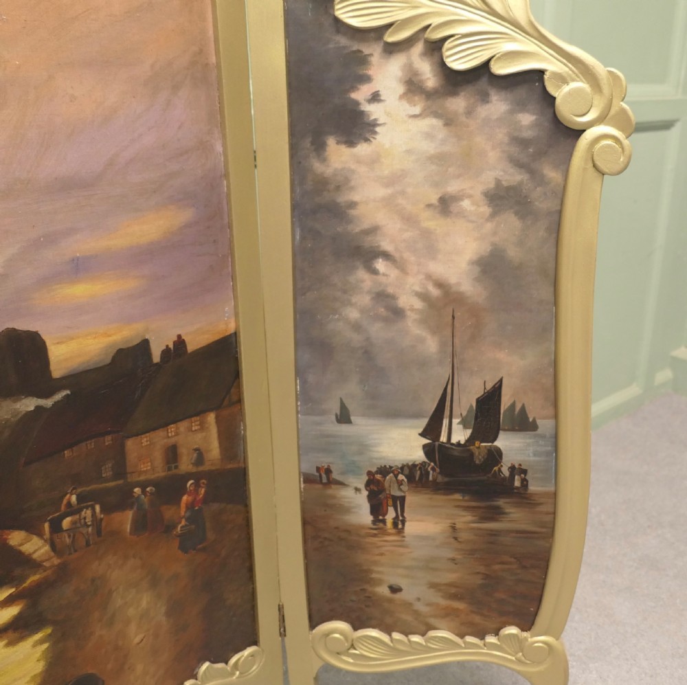 A three-panel folding fire screen with a carved gold giltwood frame and oil-painted maritime scenes depicting ships near a coastal shore at sunset. View V