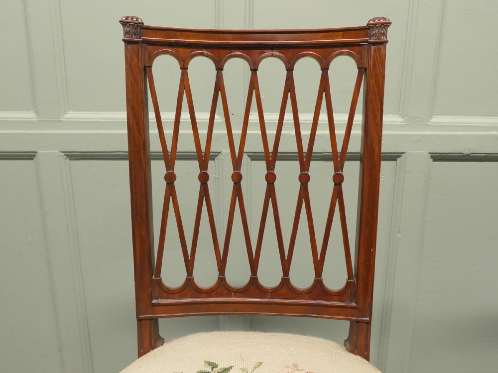A pair of antique walnut hall chairs with lattice openwork backs and floral needlepoint upholstered seats. View VI