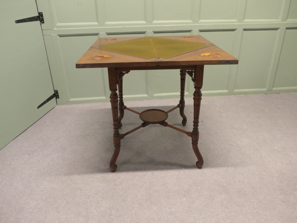 A late Victorian mahogany envelope card table with four triangular flaps unfolding to reveal a central green baize surface and four circular counter wells.