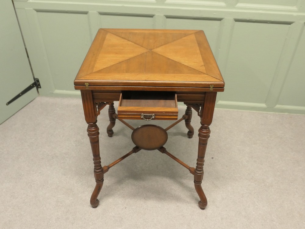 A late Victorian mahogany envelope card table with four triangular flaps unfolding to reveal a central green baize surface and four circular counter wells. View III