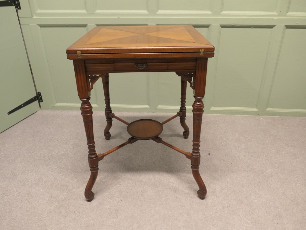 A late Victorian mahogany envelope card table with four triangular flaps unfolding to reveal a central green baize surface and four circular counter wells. View VII