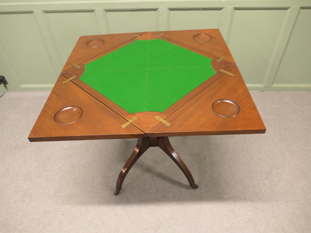A Victorian mahogany envelope card table featuring four triangular folding top leaves, a single drawer with brass handles, and a turned central pedestal on four splayed legs with castors. View III