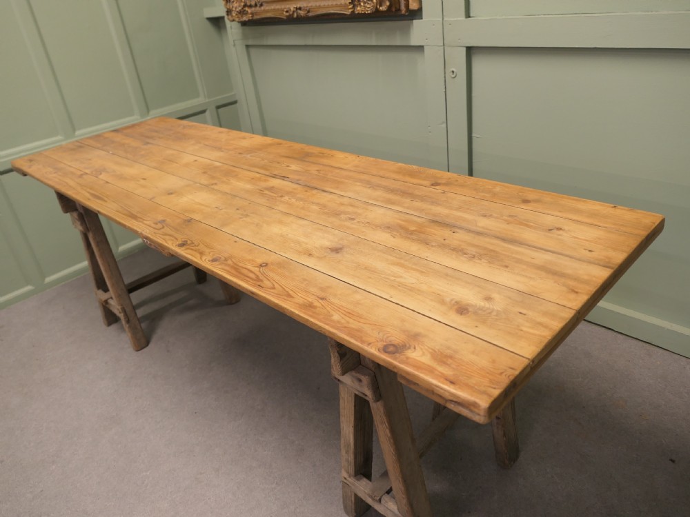 A long rustic elm harvest table featuring a simple solid plank top supported by twin wooden A-frame trestle legs. View II