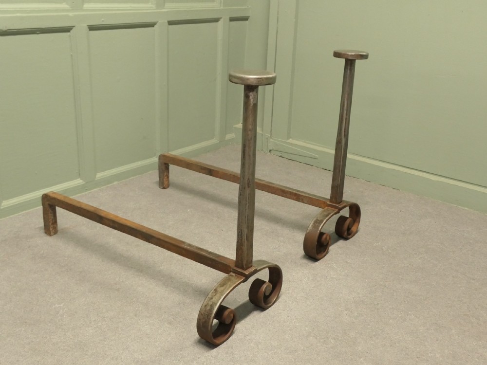 A heavy dark iron fireplace grate featuring scrolled front feet, twin upright pillar posts with flat circular tops, and a curved central log basket. View II