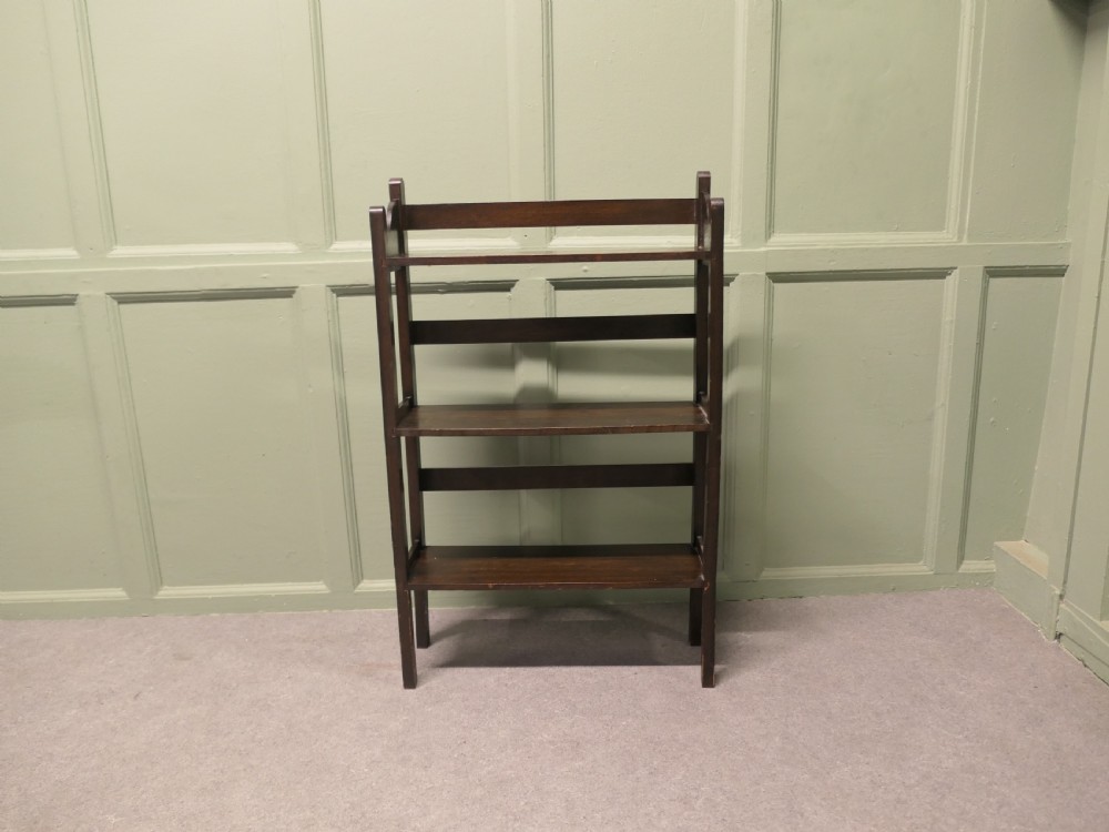 A dark oak three-shelf open bookcase with shaped side profiles and horizontal support rails. View III