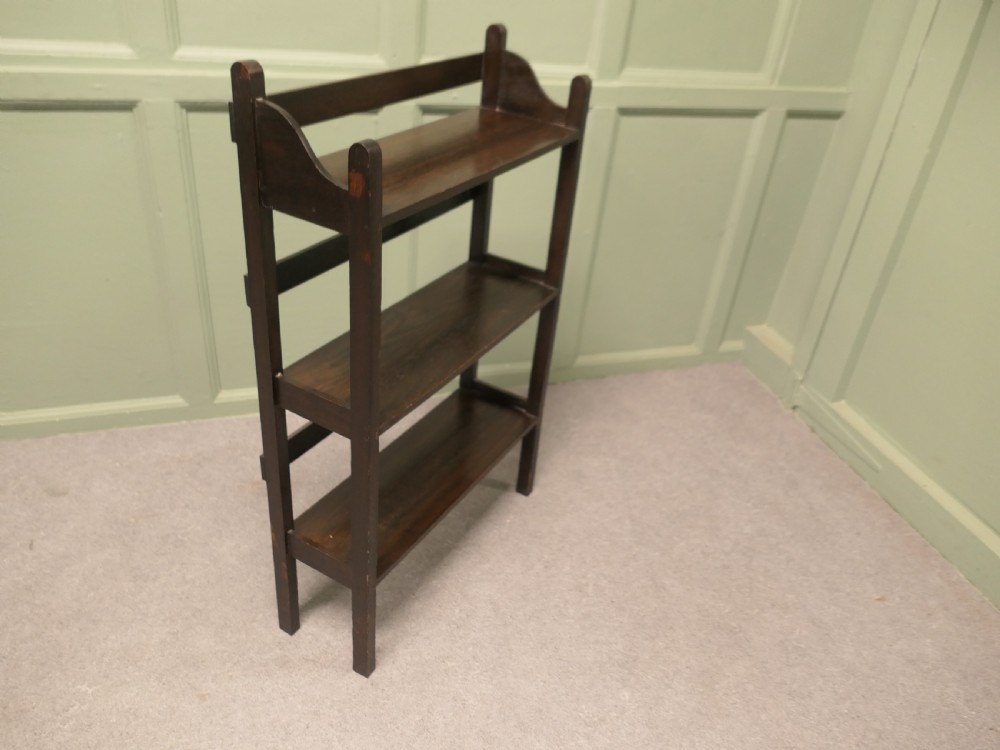 A dark oak three-shelf open bookcase with shaped side profiles and horizontal support rails. View V