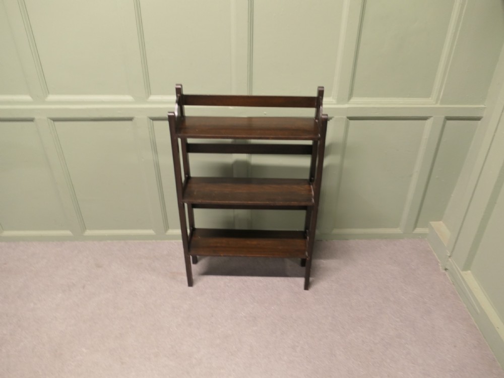 A dark oak three-shelf open bookcase with shaped side profiles and horizontal support rails. View VI