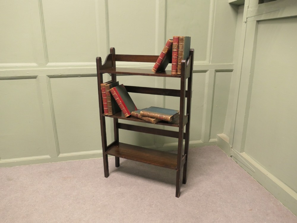 A dark oak three-shelf open bookcase with shaped side profiles and horizontal support rails. View VII