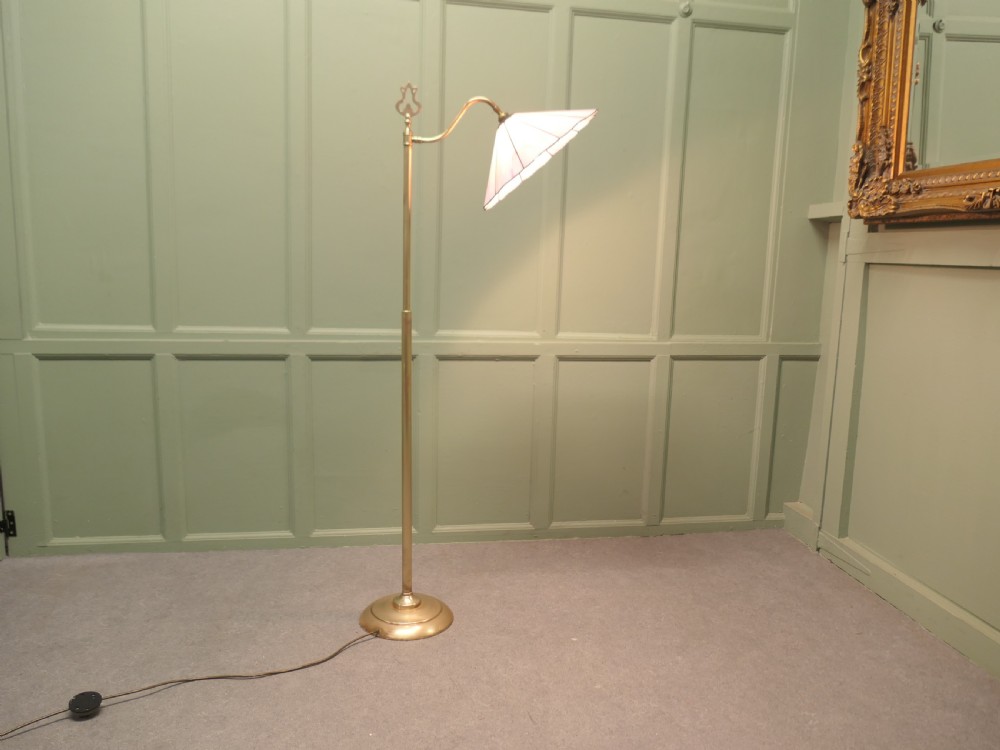 An Edwardian brass floor standing reading lamp featuring a swivel arm, weighted circular base, and a scalloped pink shade. View III