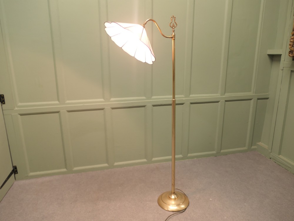 An Edwardian brass floor standing reading lamp featuring a swivel arm, weighted circular base, and a scalloped pink shade. View VI