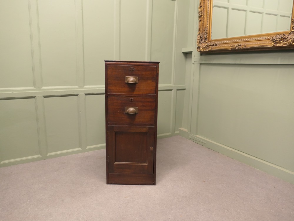A narrow 19th-century mahogany bankers pedestal cabinet featuring two upper drawers with brass cup handles and a single panelled cupboard below.