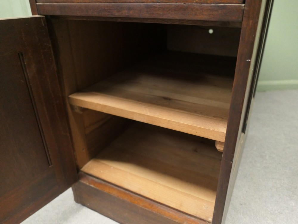 A narrow 19th-century mahogany bankers pedestal cabinet featuring two upper drawers with brass cup handles and a single panelled cupboard below. View V