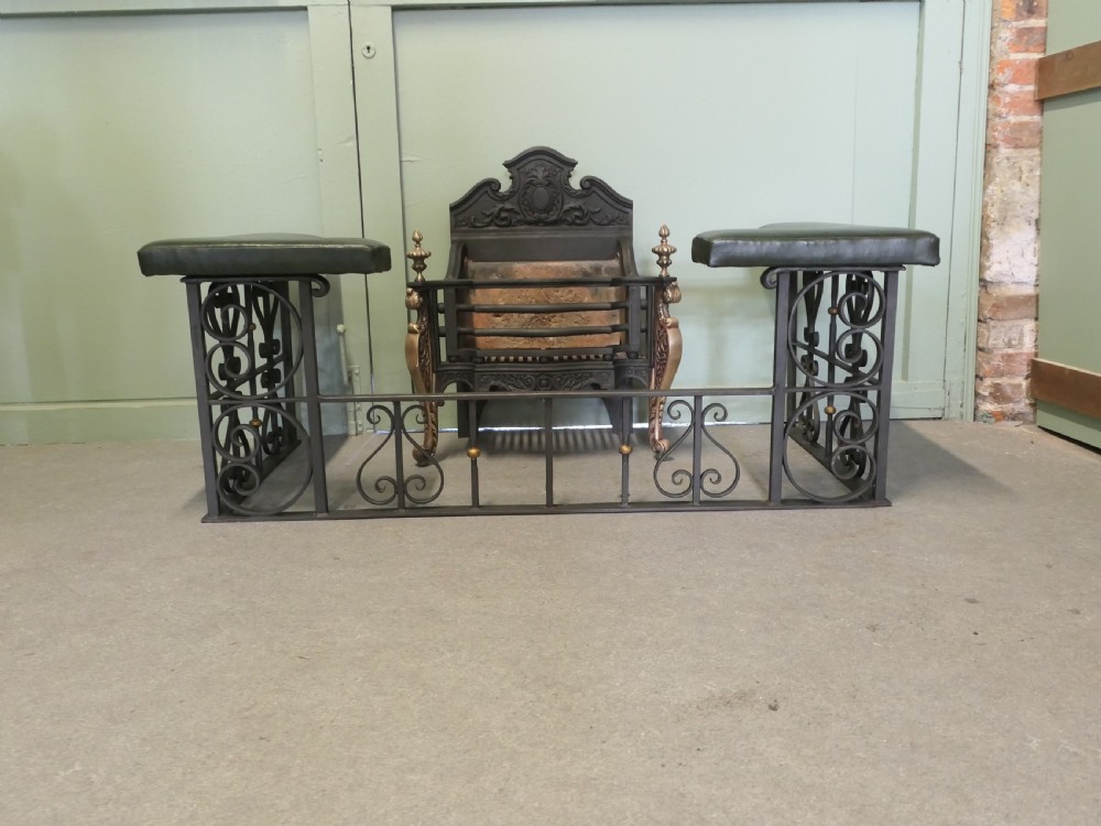 A freestanding cast iron fire basket with brass scroll legs, urn finials, an ornate crest backplate, and an internal firebrick lining. View VII