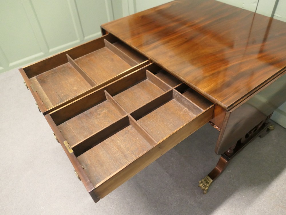 A Regency mahogany sofa table featuring two drop leaves, dual frieze drawers with brass handles, and lyre-shaped end supports terminating in brass lion paw castors. View III