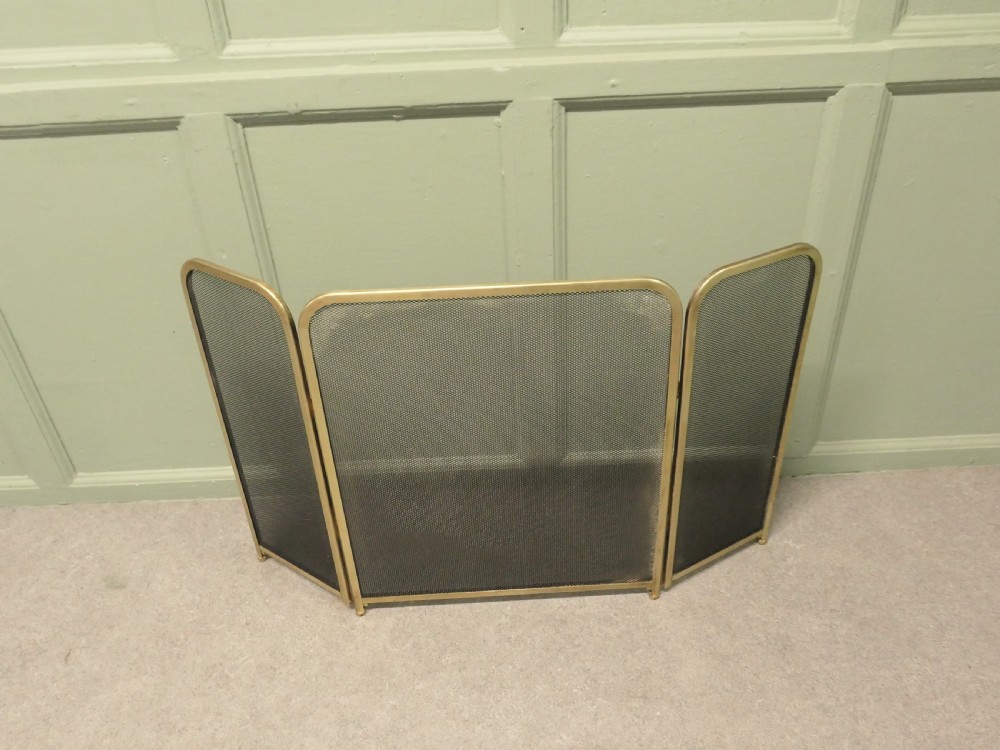 A three-panel folding fire guard featuring a tubular brass frame with black wire mesh screen inserts. View VI