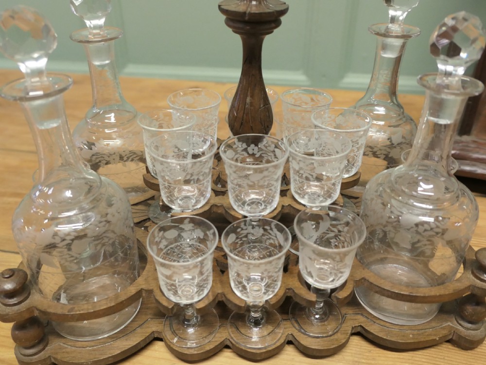 A carved wooden Black Forest liqueur box with glass panels enclosing etched glass decanters and small glasses. View II