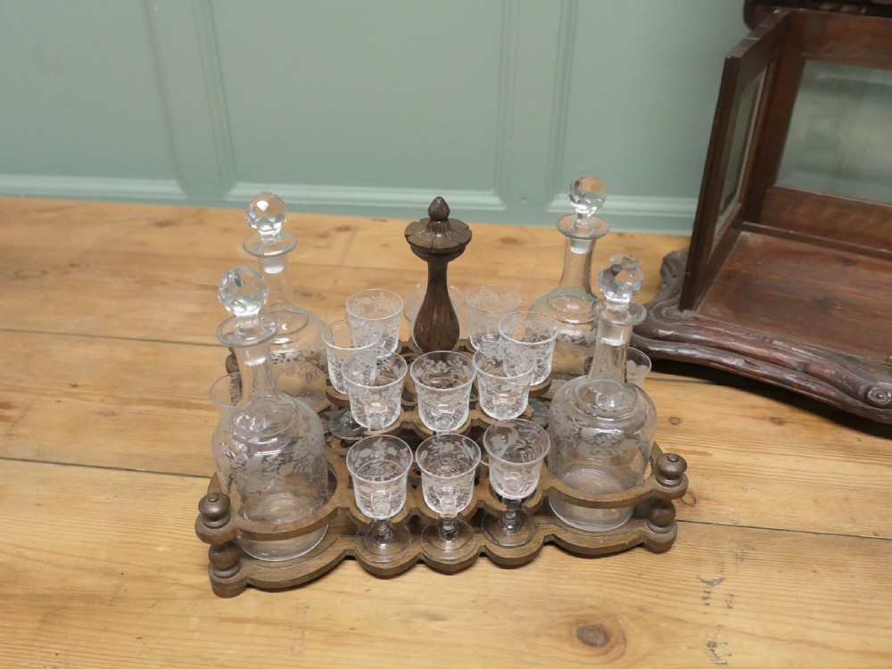 A carved wooden Black Forest liqueur box with glass panels enclosing etched glass decanters and small glasses. View III