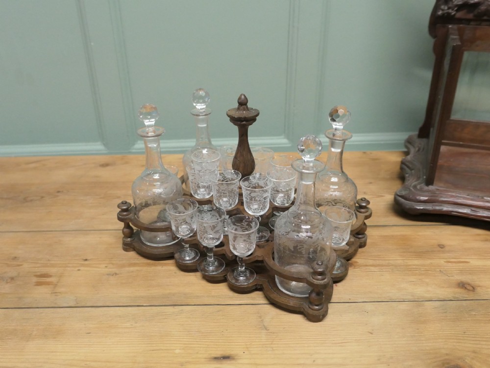 A carved wooden Black Forest liqueur box with glass panels enclosing etched glass decanters and small glasses. View VI