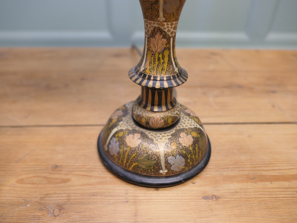 A tall hand-painted turned wooden candlestick table lamp with detailed gold and black patterns, fitted with a faux candle column and a pleated cream lampshade. View II