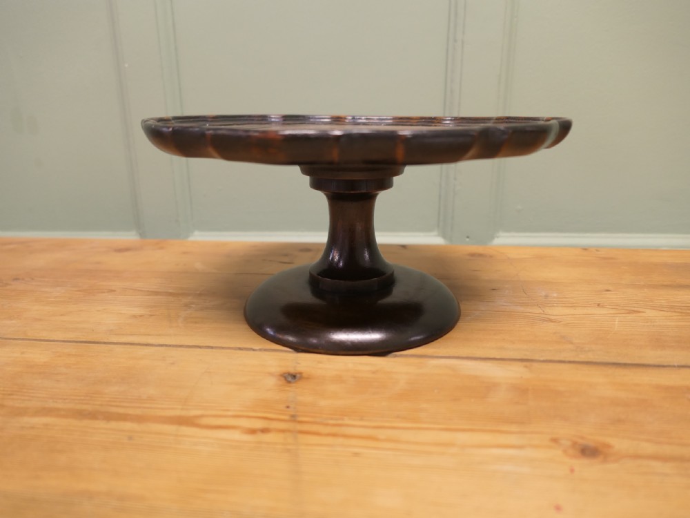 A dark oak Art Deco tazza featuring a scalloped circular tray top supported by a turned pedestal base.