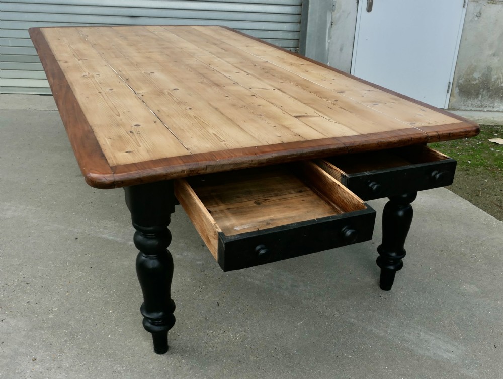 A large Victorian pine farmhouse dining table featuring a natural wood top with dark trim and a black painted base with four turned legs. View II