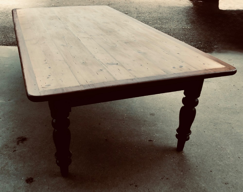 A large Victorian pine farmhouse dining table featuring a natural wood top with dark trim and a black painted base with four turned legs. View IV